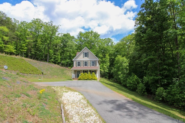 view of front of home with driveway and a view of trees
