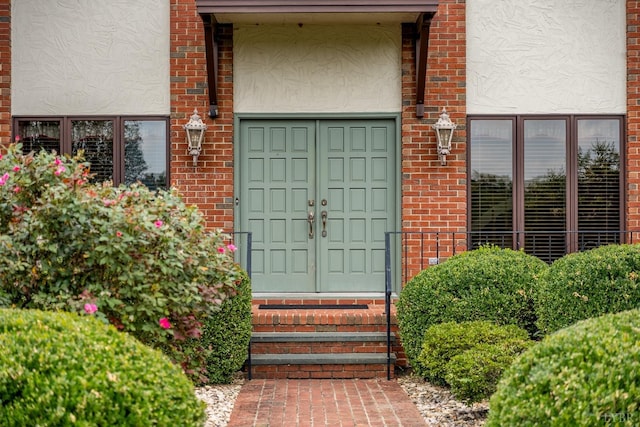doorway to property with stucco siding and brick siding