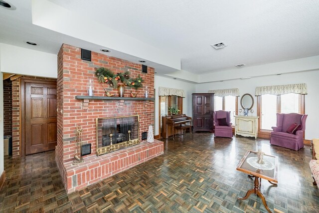 living area with a textured ceiling, a fireplace, and visible vents
