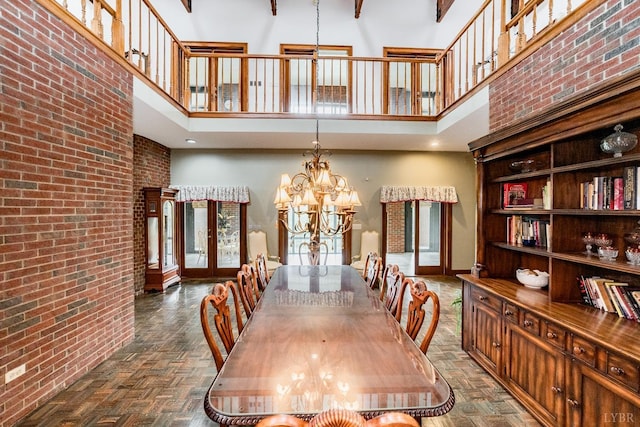 dining area featuring an inviting chandelier, brick wall, and a high ceiling