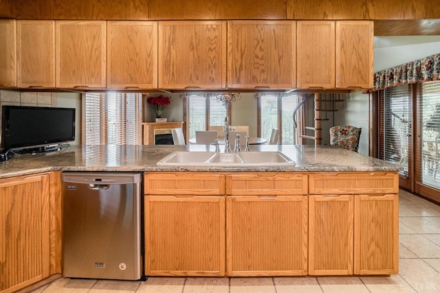 kitchen featuring a sink, light stone countertops, a fireplace, and stainless steel dishwasher