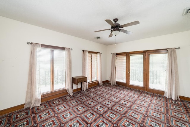 unfurnished room featuring a ceiling fan, baseboards, and visible vents