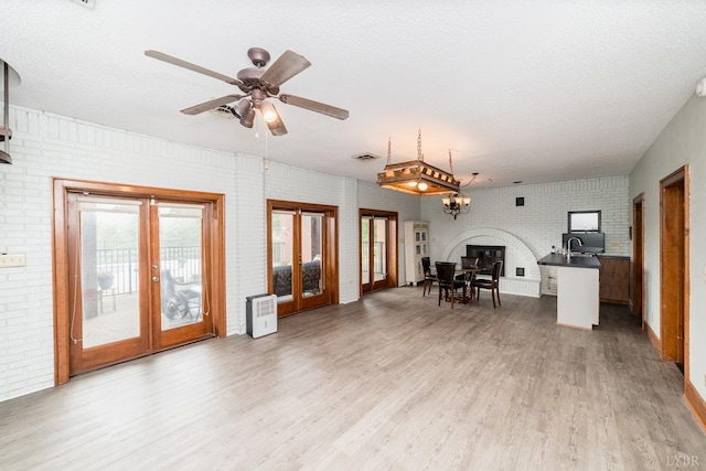 interior space featuring visible vents, light wood-style flooring, french doors, and brick wall