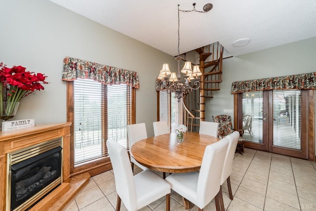 dining space featuring a glass covered fireplace, an inviting chandelier, and light tile patterned floors
