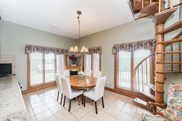 dining area featuring baseboards, a fireplace, a notable chandelier, lofted ceiling, and light tile patterned floors