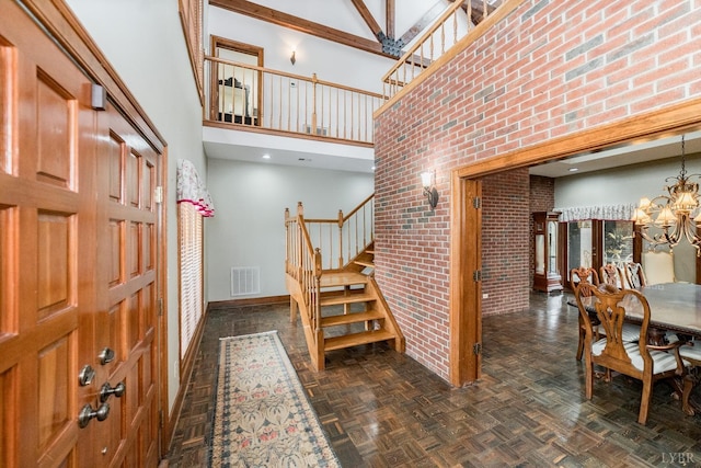 entryway featuring stairs, baseboards, visible vents, a towering ceiling, and an inviting chandelier