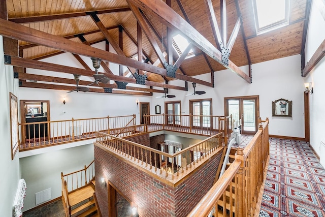 stairway with high vaulted ceiling, wooden ceiling, beam ceiling, baseboards, and ceiling fan