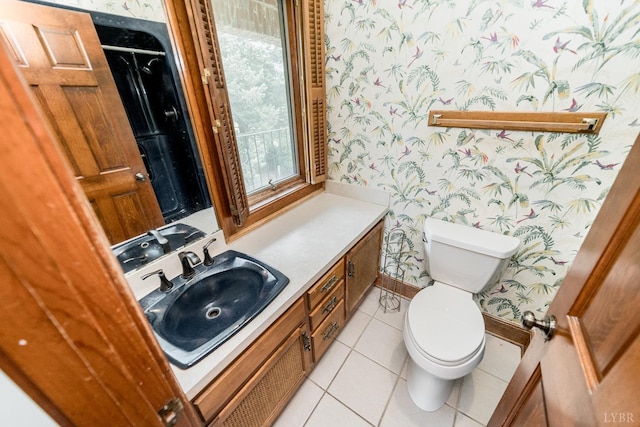 half bath featuring tile patterned floors, toilet, vanity, baseboards, and wallpapered walls