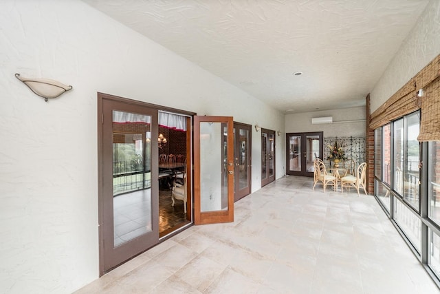 unfurnished sunroom featuring a wall mounted air conditioner and french doors