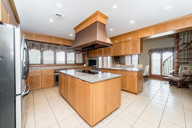 kitchen with appliances with stainless steel finishes, a peninsula, light tile patterned floors, island exhaust hood, and visible vents