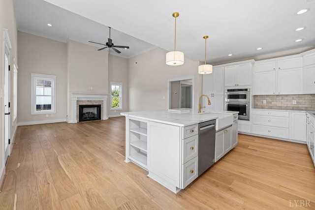 kitchen featuring a ceiling fan, white cabinets, decorative backsplash, stainless steel appliances, and a kitchen island with sink