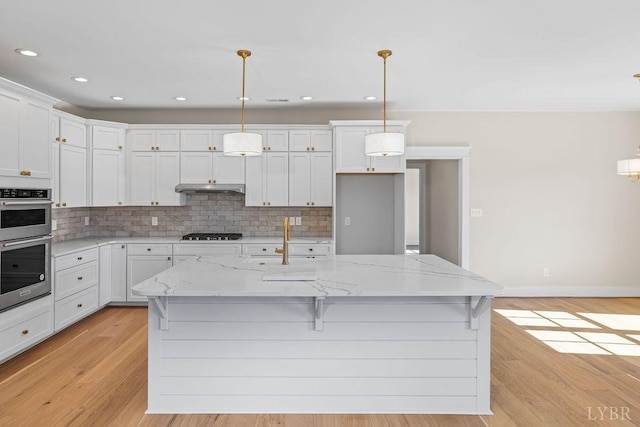 kitchen featuring a sink, decorative backsplash, under cabinet range hood, and gas cooktop