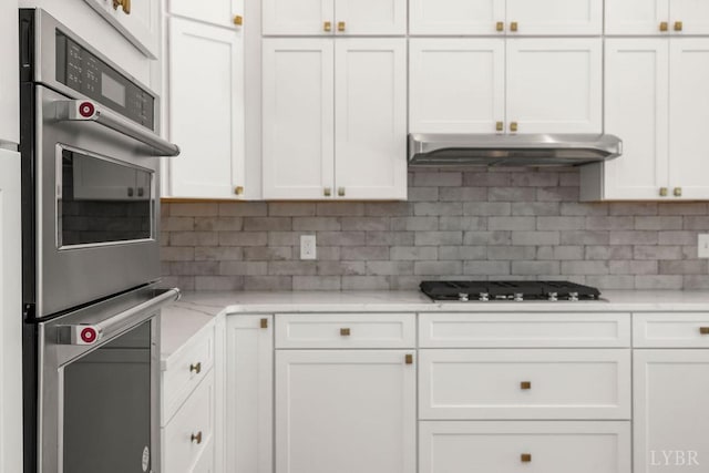 kitchen with double oven, gas cooktop, under cabinet range hood, backsplash, and white cabinets