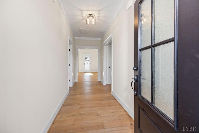 hall featuring baseboards, ornamental molding, and light wood-style flooring