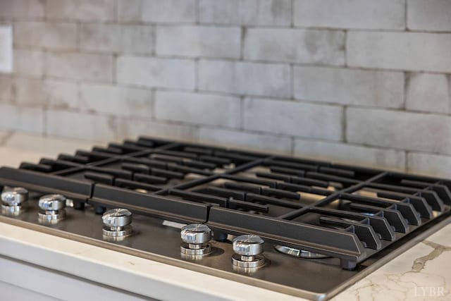 details with decorative backsplash and stainless steel gas cooktop