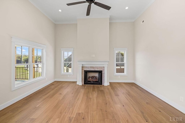 unfurnished living room with crown molding, plenty of natural light, baseboards, and a high ceiling