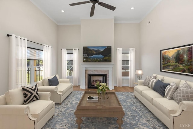 living room featuring wood finished floors, a towering ceiling, recessed lighting, a fireplace, and ceiling fan
