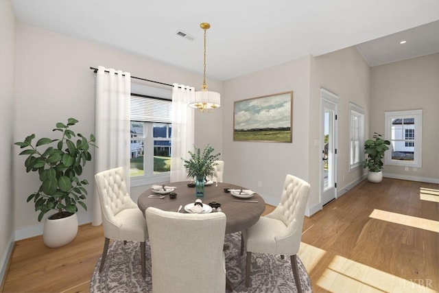 dining space with plenty of natural light, a chandelier, and light wood-type flooring