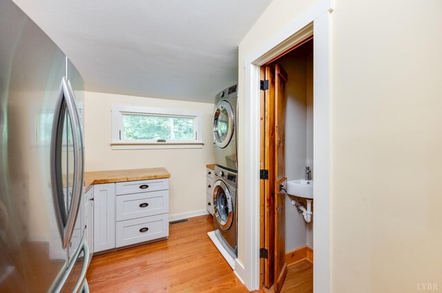 1343 Wares Gap Rd, Monroe, VA 24574 - clothes washing area featuring stacked washer / drying machine, baseboards, a sink, light wood finished floors, and laundry area
