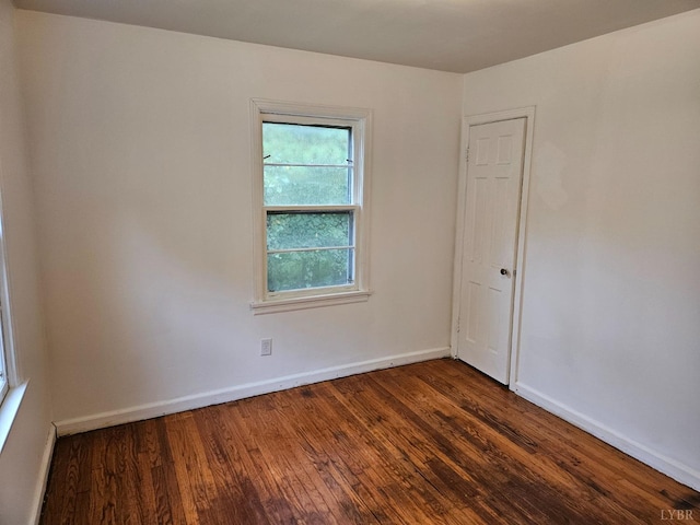 empty room featuring baseboards and dark wood finished floors