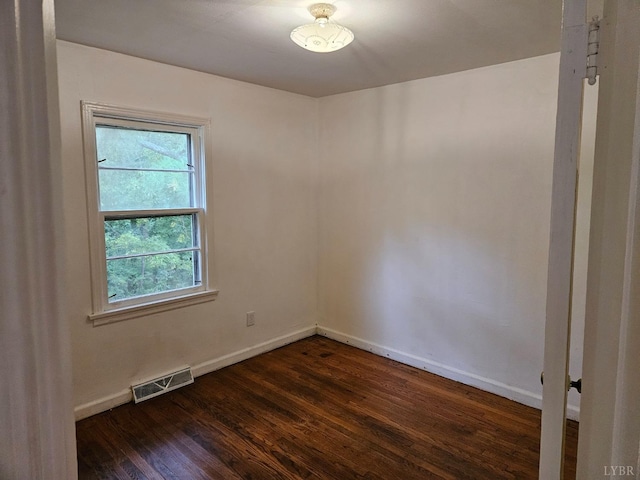 empty room with baseboards, visible vents, and dark wood-type flooring