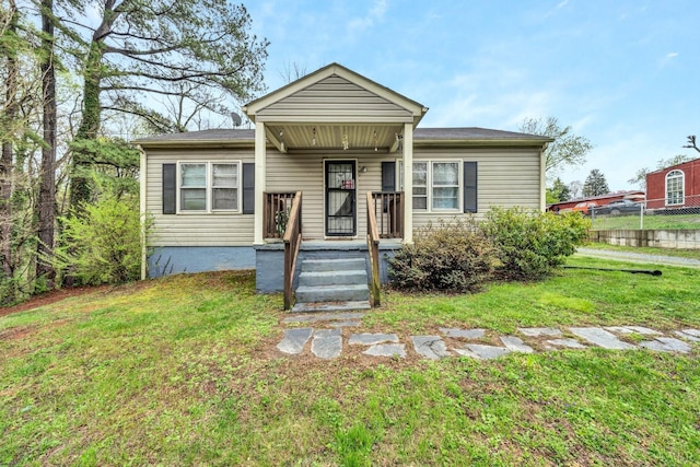 bungalow featuring covered porch, fence, and a front yard