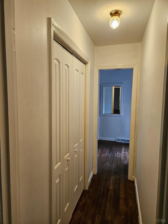 hallway with visible vents, dark wood-style flooring, and baseboards