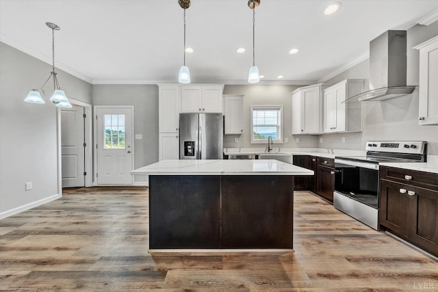 kitchen with wall chimney range hood, crown molding, appliances with stainless steel finishes, and plenty of natural light