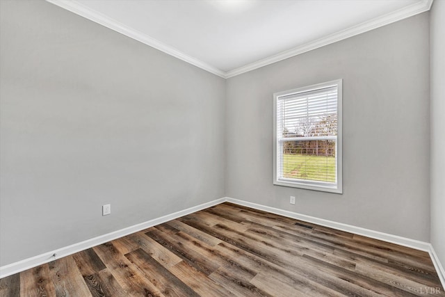 spare room with dark wood-style flooring, baseboards, visible vents, and ornamental molding