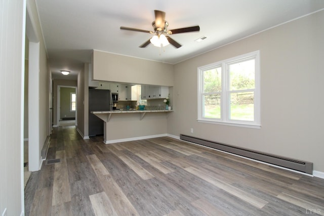 5427 Snake Creek Rd, Stuart, VA 24343 - unfurnished living room featuring a ceiling fan, visible vents, wood finished floors, and a baseboard radiator