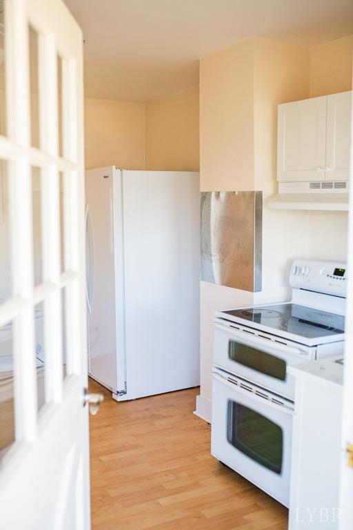 67 Lentz Ln, Shipman, VA 22971 - kitchen with white appliances, under cabinet range hood, light wood-style flooring, and white cabinetry