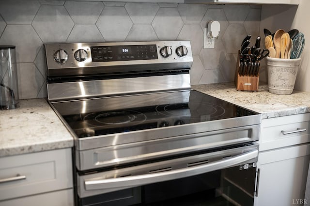 3047 Fulton St, Lynchburg, VA 24501 - kitchen view of stainless steel electric range, decorative backsplash, white cabinetry, and light stone countertops