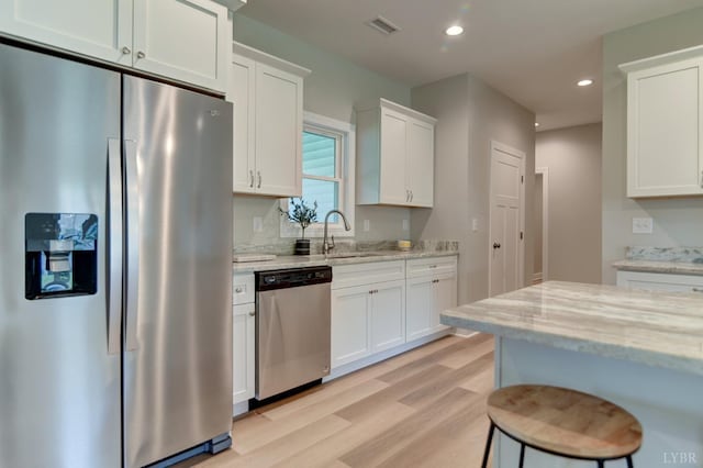 1327 Greenhouse Rd, Rustburg, VA 24588 - kitchen featuring light stone countertops, light wood finished floors, a sink, white cabinets, and appliances with stainless steel finishes