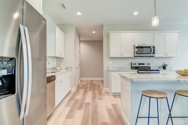 1327 Greenhouse Rd, Rustburg, VA 24588 - kitchen with a breakfast bar area, a sink, light wood-style floors, stainless steel appliances, and white cabinets