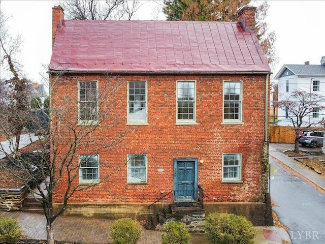 colonial house with a chimney and brick siding