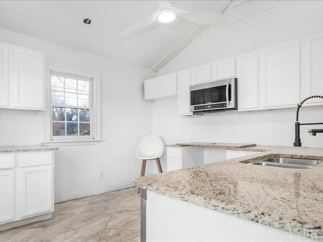 522 Jackson St, Lynchburg, VA 24504 - kitchen with light stone counters, a sink, white cabinets, vaulted ceiling, and stainless steel microwave