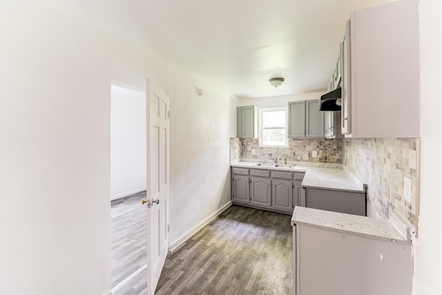 1930 Vine St, Lynchburg, VA 24501 - kitchen featuring decorative backsplash, wood finished floors, under cabinet range hood, a sink, and gray cabinetry