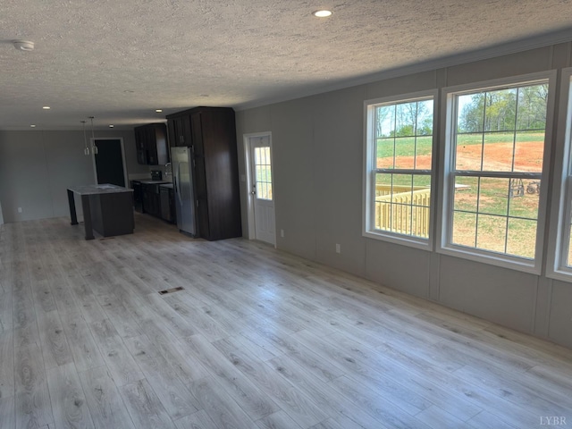 unfurnished living room with a textured ceiling, light wood-style flooring, and recessed lighting