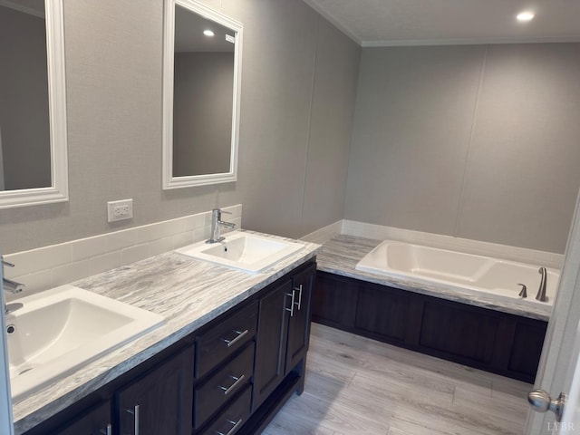 full bathroom with wood finished floors, double vanity, backsplash, a garden tub, and crown molding
