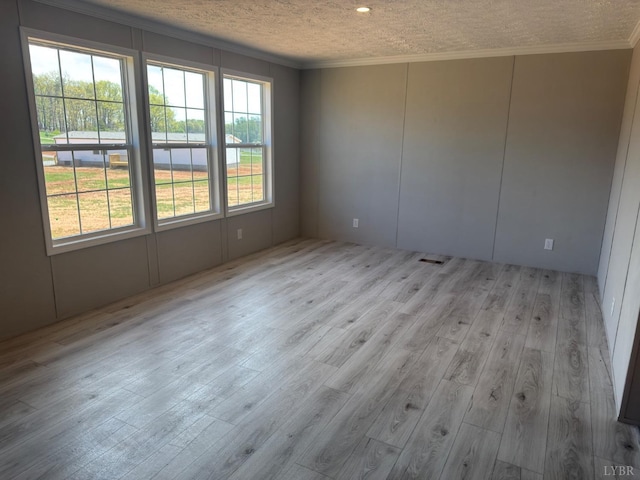 unfurnished room with crown molding, wood finished floors, a decorative wall, and a textured ceiling