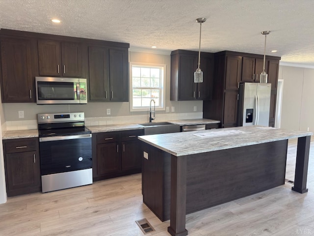 kitchen featuring appliances with stainless steel finishes, a sink, dark brown cabinetry, crown molding, and light wood finished floors