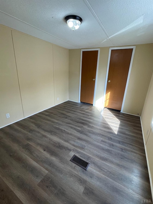 unfurnished room featuring dark wood-style flooring and a textured ceiling