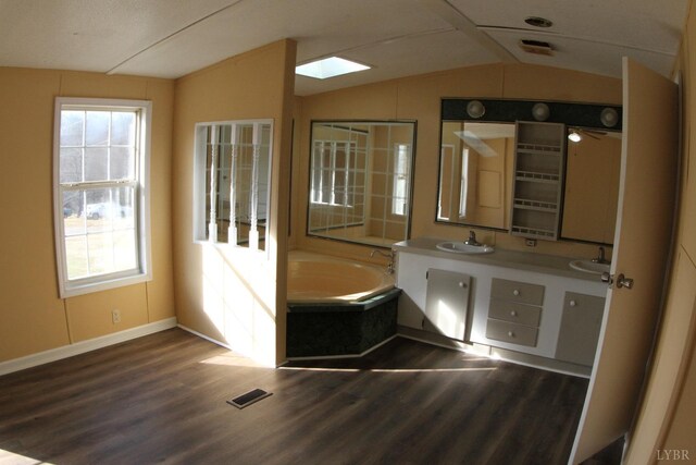 bathroom with lofted ceiling, wood finished floors, baseboards, a bath, and healthy amount of natural light