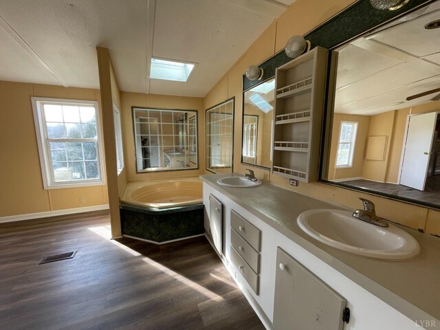 full bathroom with wood finished floors, healthy amount of natural light, double vanity, and a garden tub