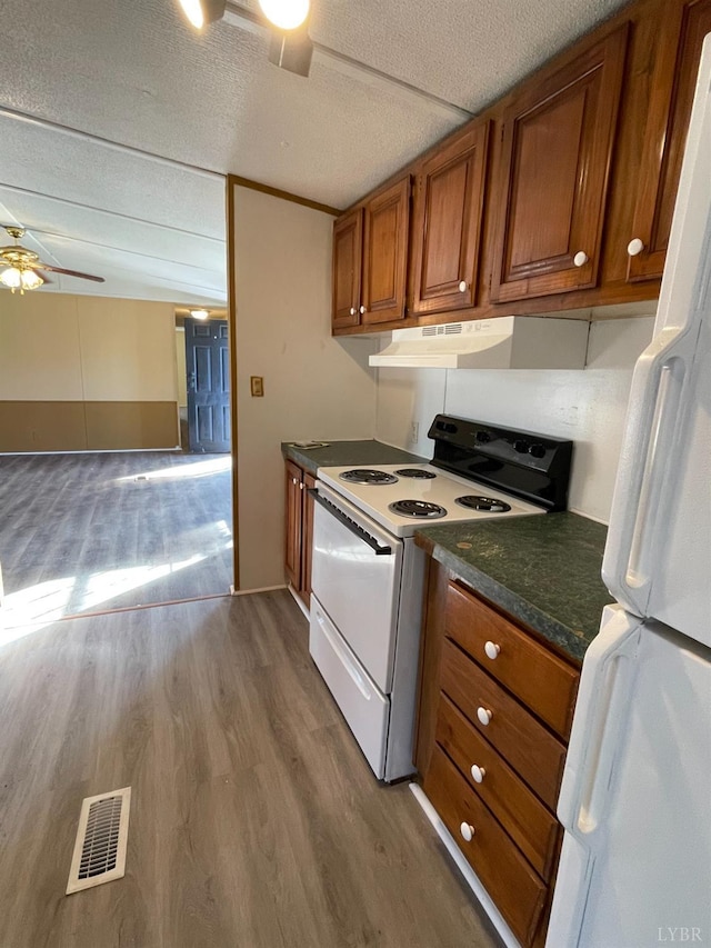kitchen with white appliances, brown cabinets, ceiling fan, range hood, and dark countertops