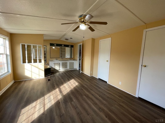 unfurnished living room featuring wood finished floors, ceiling fan, vaulted ceiling, baseboards, and a textured ceiling