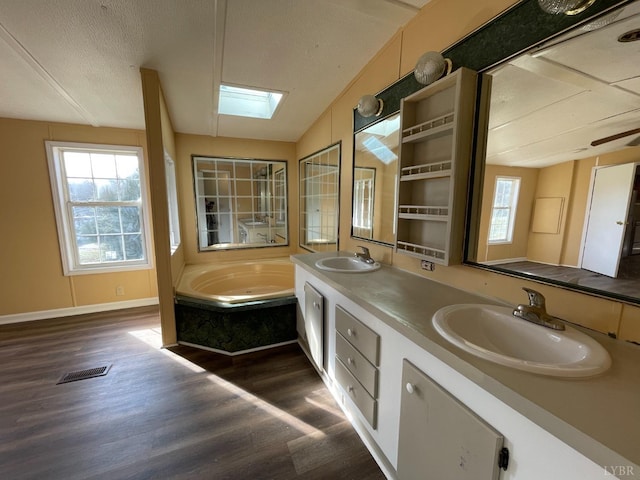 full bath with wood finished floors, plenty of natural light, double vanity, and a garden tub