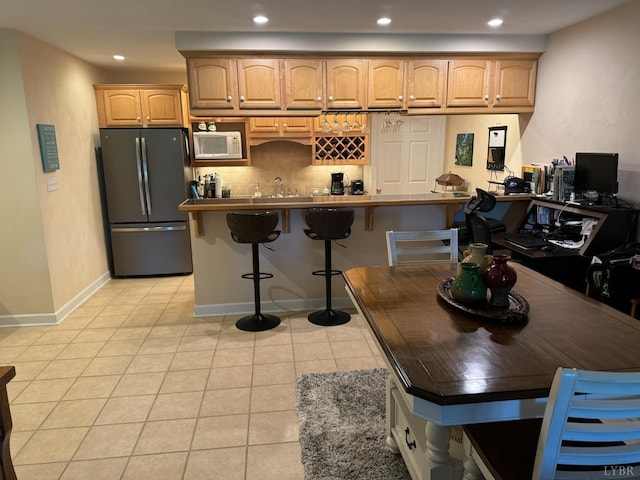 206 Blarney Stone Ct, Huddleston, VA 24104 - kitchen with freestanding refrigerator, white microwave, decorative backsplash, light tile patterned flooring, and a kitchen breakfast bar