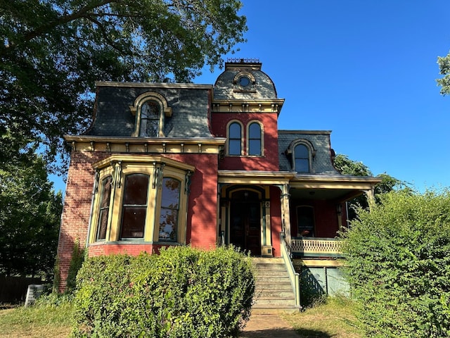 second empire-style home with covered porch, mansard roof, and brick siding