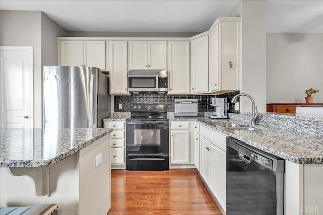 59 Broad St, Daleville, VA 24083 - kitchen with a peninsula, white cabinetry, light stone counters, a sink, and appliances with stainless steel finishes